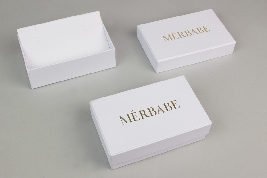 Λευκό κουτί κοσμημάτων MÉRBABE με εκτύπωση του λογότυπου της εταιρείας στο καπάκι (χρυσαφένια απόχρωση).